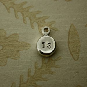 Flat, round nugget hand stamped with number 18