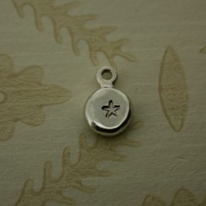 silver pebble charm hand stamped with a star shape