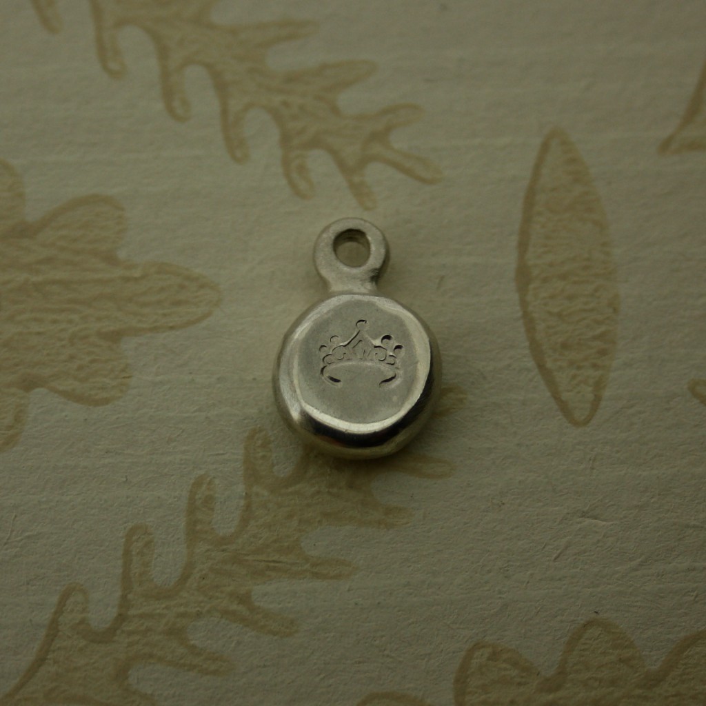 silver pebble charm hand stamped with a tiara symbol