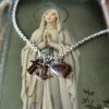 small silver heart and anchor strung on a silver chain with a small gold cross