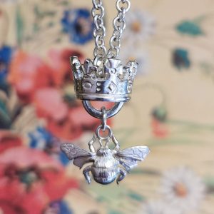 Bumblebee charm hanging under a jubilee crown from a long chain necklace
