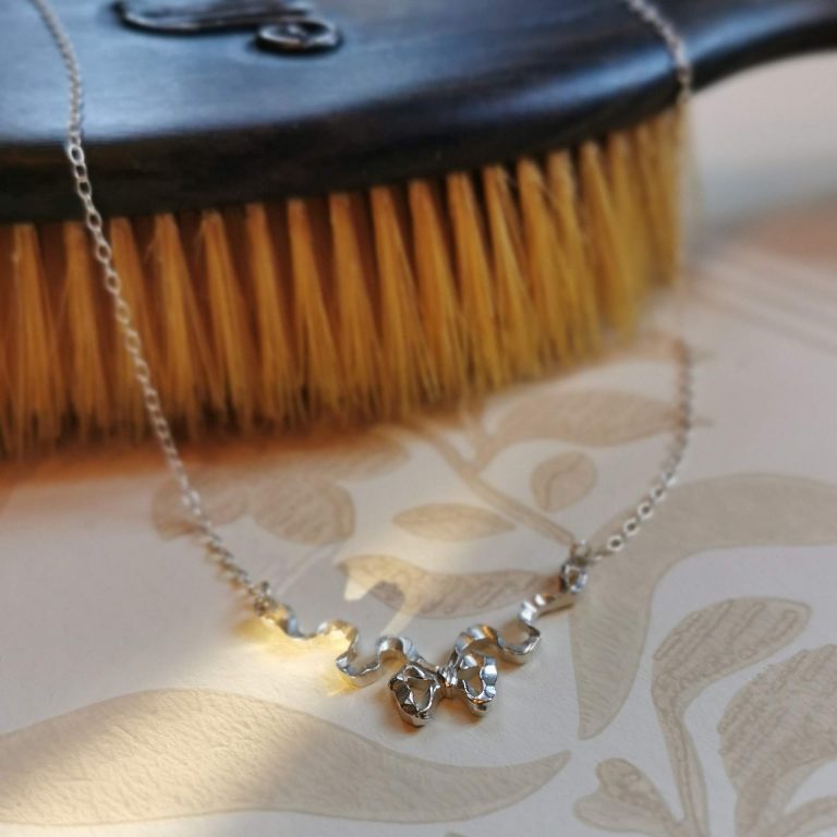 silver bow featuring in the middle of a fine trace necklace